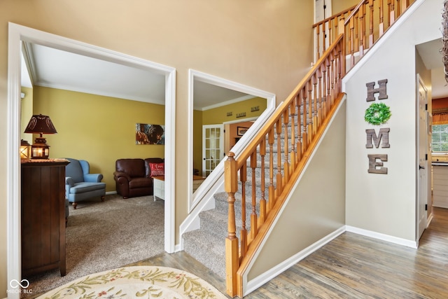 stairway with ornamental molding and hardwood / wood-style floors