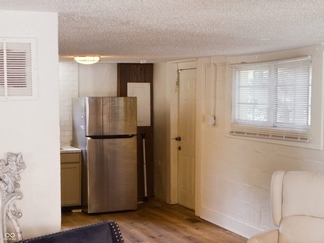 kitchen with a textured ceiling, stainless steel fridge, and light wood-type flooring