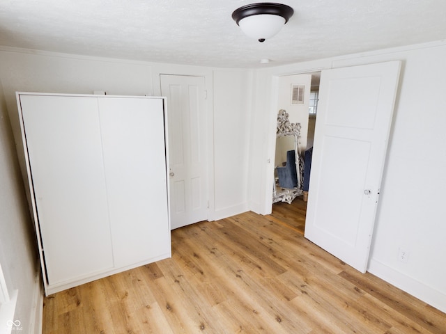 unfurnished bedroom with a textured ceiling and light hardwood / wood-style floors