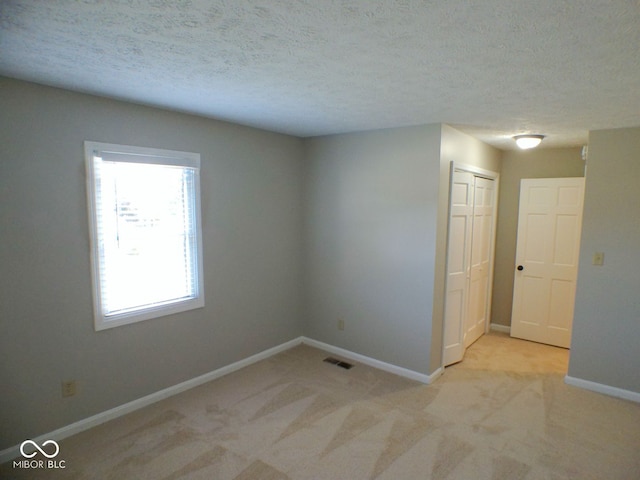 carpeted spare room with a textured ceiling