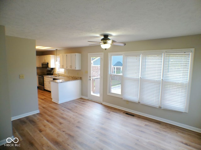 kitchen with hardwood / wood-style floors, stainless steel appliances, white cabinetry, ceiling fan, and a textured ceiling