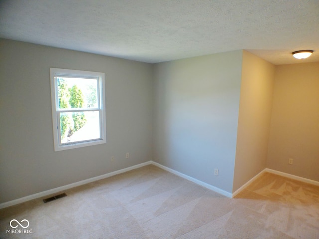 carpeted empty room featuring a textured ceiling