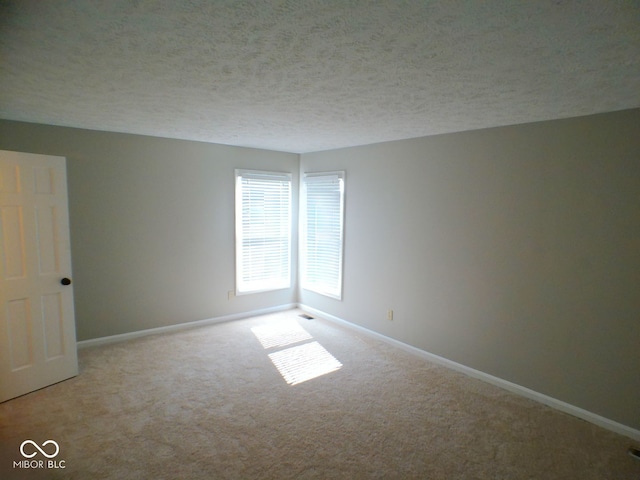 carpeted empty room with a textured ceiling