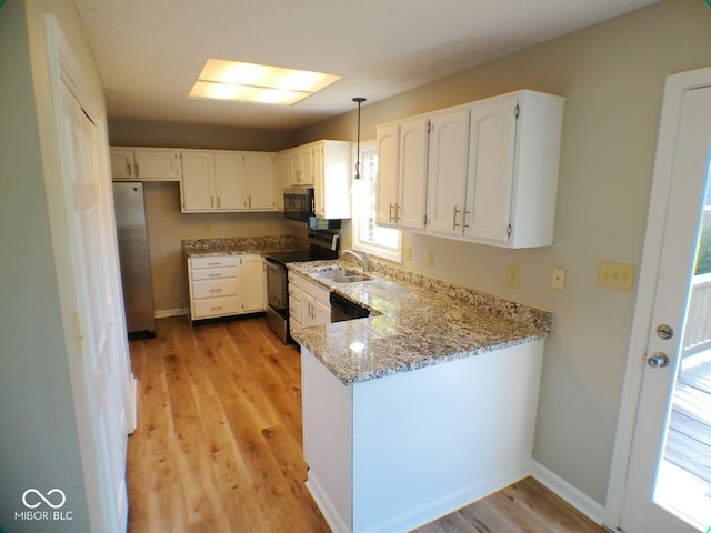 kitchen with light wood-type flooring, stainless steel appliances, light stone counters, sink, and white cabinets