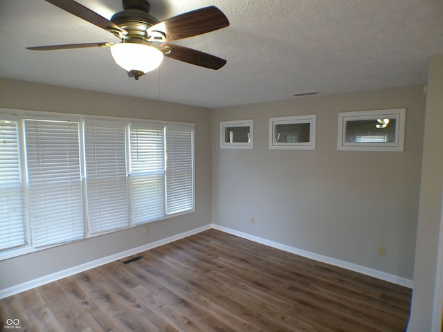 spare room with dark wood-type flooring, ceiling fan, and a textured ceiling