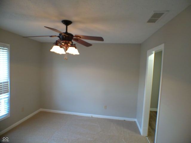 carpeted empty room featuring ceiling fan and a wealth of natural light