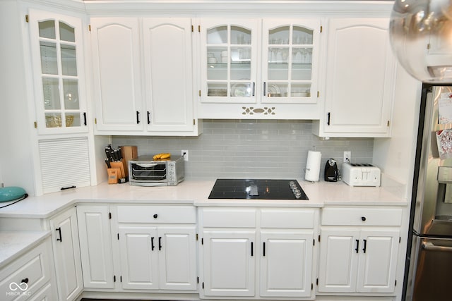 kitchen featuring stainless steel fridge with ice dispenser, white cabinetry, black electric stovetop, and tasteful backsplash