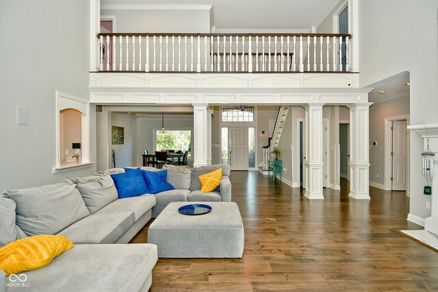 living room with a towering ceiling, decorative columns, dark hardwood / wood-style flooring, and ornamental molding