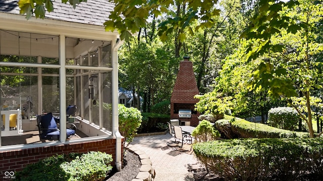 view of patio featuring a fireplace and a sunroom