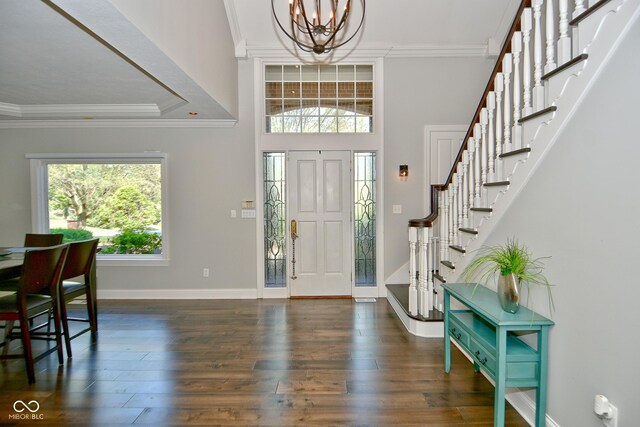 foyer entrance featuring a wealth of natural light, crown molding, a notable chandelier, and dark hardwood / wood-style flooring