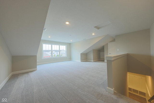 bonus room with lofted ceiling and light carpet