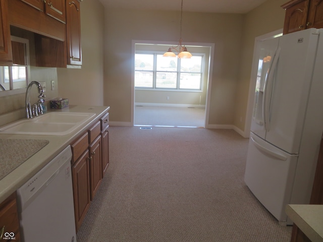 kitchen with hanging light fixtures, sink, light carpet, and white appliances