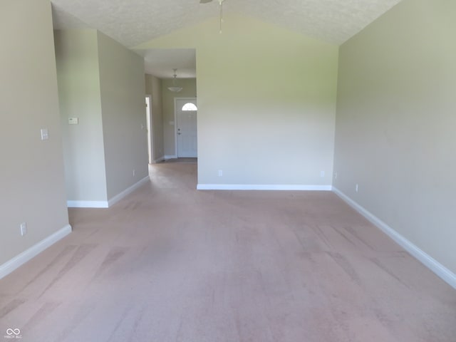 empty room with lofted ceiling, ceiling fan, light carpet, and a textured ceiling