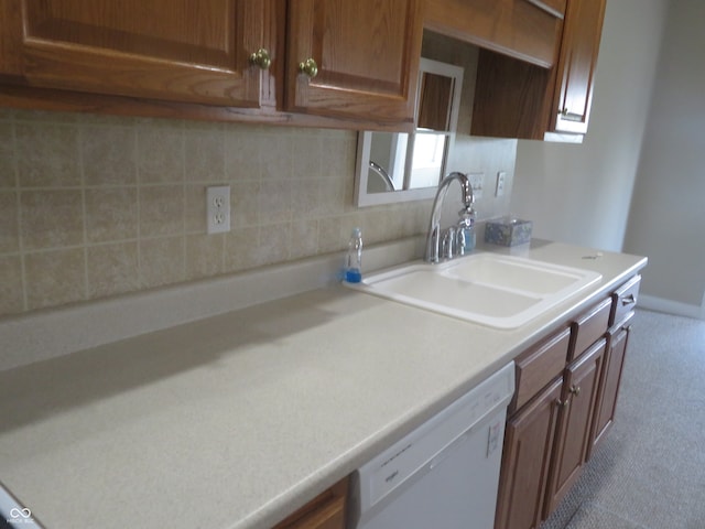 kitchen featuring tasteful backsplash, white dishwasher, and sink