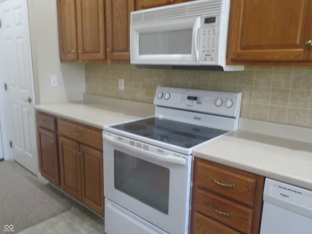 kitchen with light tile patterned floors, white appliances, and decorative backsplash