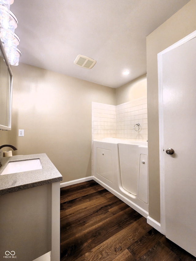 bathroom featuring a bathing tub, decorative backsplash, vanity, and wood-type flooring