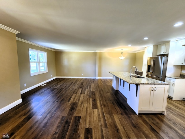 kitchen featuring white cabinets, sink, an island with sink, high quality fridge, and light stone counters