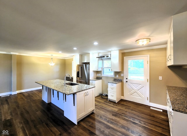 kitchen with white cabinetry, sink, stainless steel fridge with ice dispenser, pendant lighting, and a kitchen island with sink