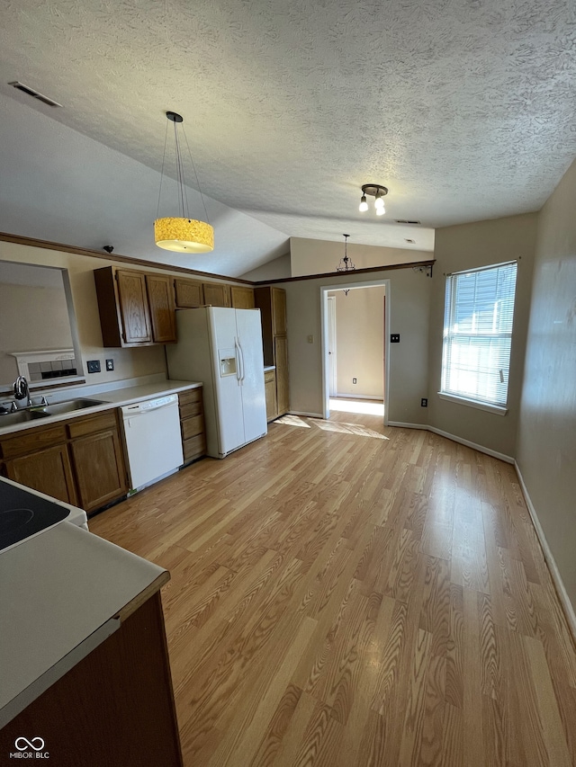 kitchen with light hardwood / wood-style floors, vaulted ceiling, sink, pendant lighting, and white appliances