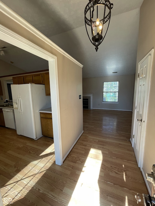 hall with light wood-type flooring, lofted ceiling, and a notable chandelier