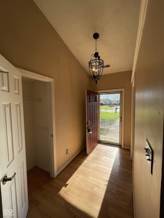 entryway with hardwood / wood-style flooring and a notable chandelier