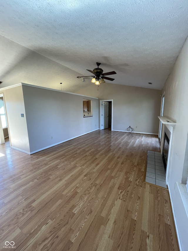 unfurnished living room with a textured ceiling, lofted ceiling, hardwood / wood-style flooring, and ceiling fan