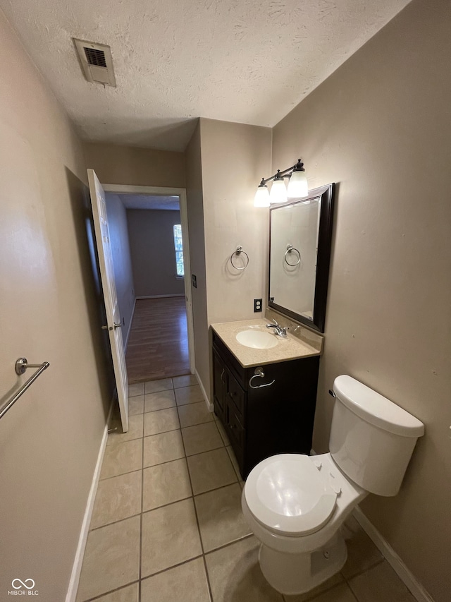 bathroom with vanity, tile patterned flooring, toilet, and a textured ceiling