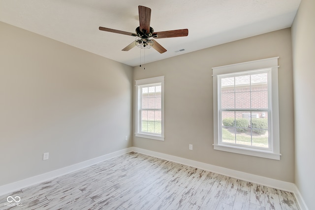 spare room featuring ceiling fan, light wood-type flooring, and plenty of natural light