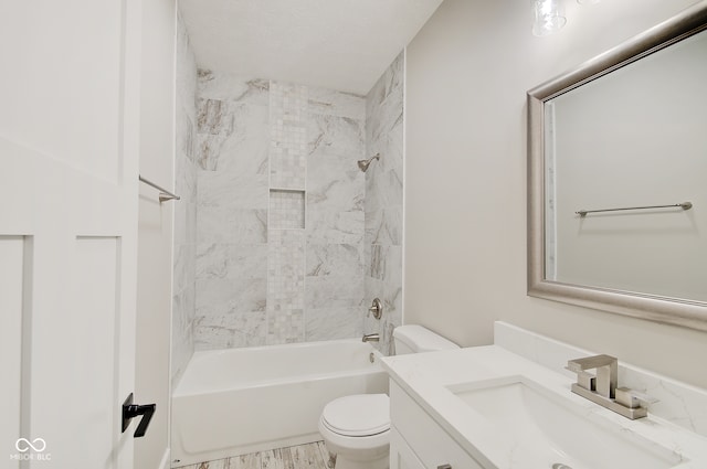 full bathroom featuring a textured ceiling, tiled shower / bath combo, vanity, and toilet