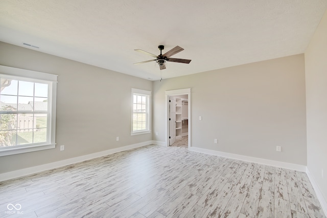 unfurnished room with light hardwood / wood-style floors, ceiling fan, plenty of natural light, and a textured ceiling