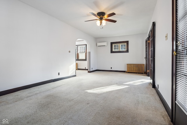 unfurnished bedroom with ceiling fan, a wall unit AC, light colored carpet, and radiator