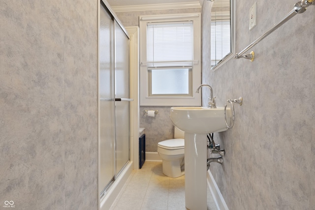 bathroom featuring toilet, a shower with shower door, and crown molding