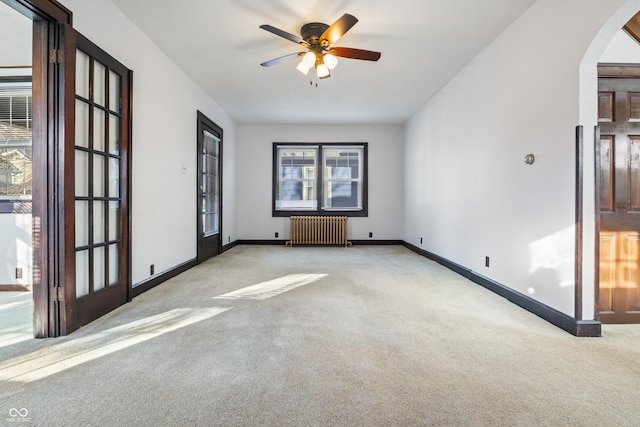 unfurnished room with ceiling fan, radiator heating unit, light carpet, and plenty of natural light