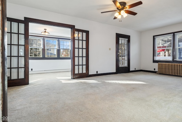 empty room featuring radiator, french doors, light colored carpet, and a baseboard heating unit