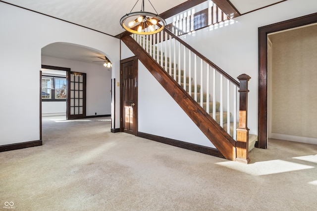 stairway featuring ceiling fan with notable chandelier, carpet floors, and baseboard heating