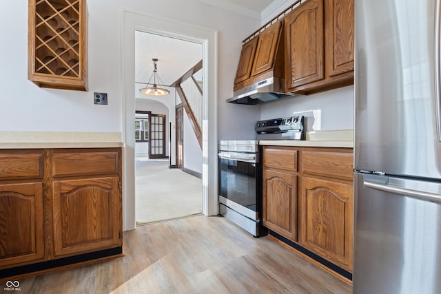 kitchen featuring crown molding, light colored carpet, a notable chandelier, and appliances with stainless steel finishes