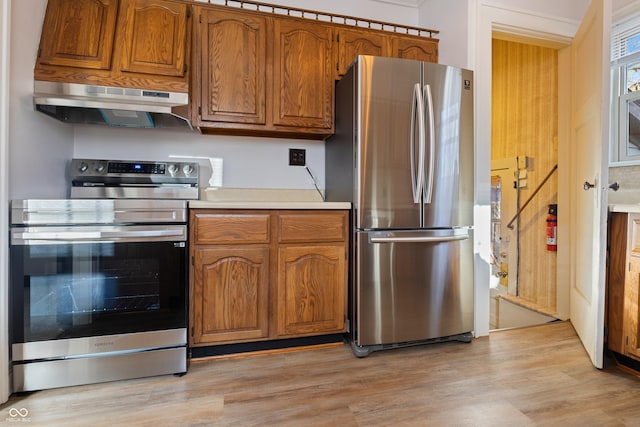 kitchen with stainless steel appliances, extractor fan, and light wood-type flooring