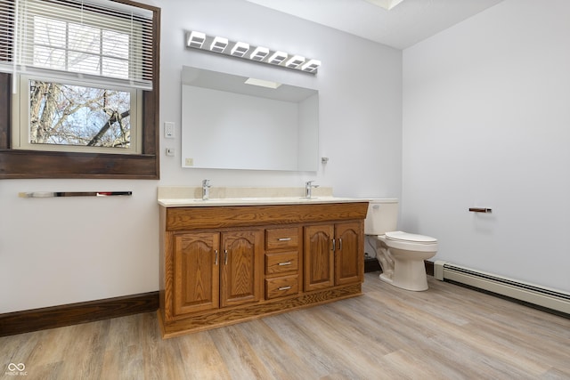 bathroom with vanity, toilet, wood-type flooring, and baseboard heating