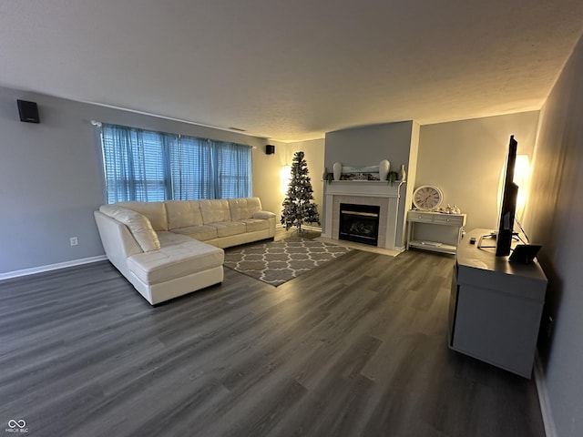 living area featuring dark wood-type flooring, a fireplace, and baseboards