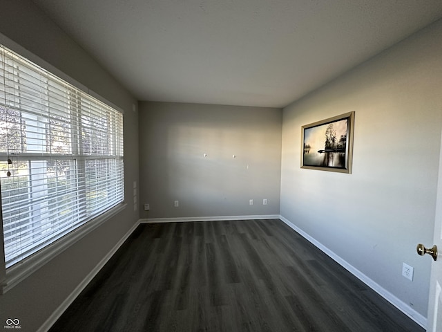 spare room featuring dark wood-type flooring and baseboards