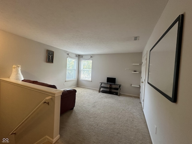 unfurnished living room featuring visible vents, a textured ceiling, baseboards, and carpet floors