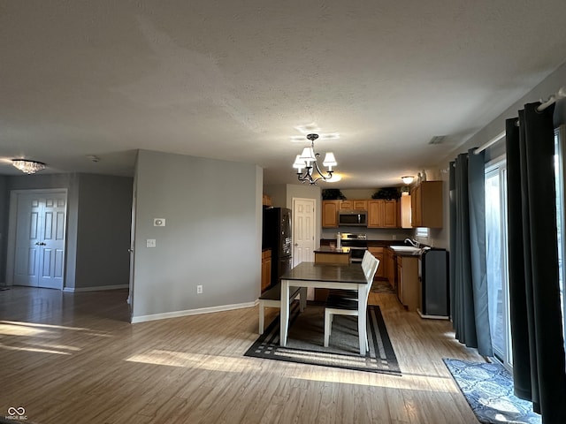 dining area featuring visible vents, baseboards, light wood-style floors, a notable chandelier, and a textured ceiling