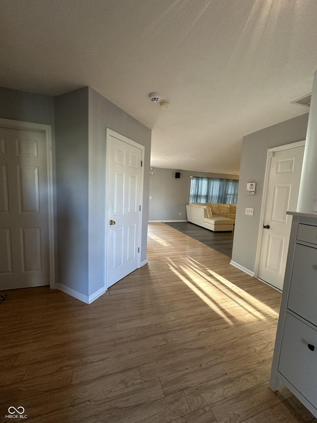 interior space with baseboards, a textured ceiling, and wood finished floors