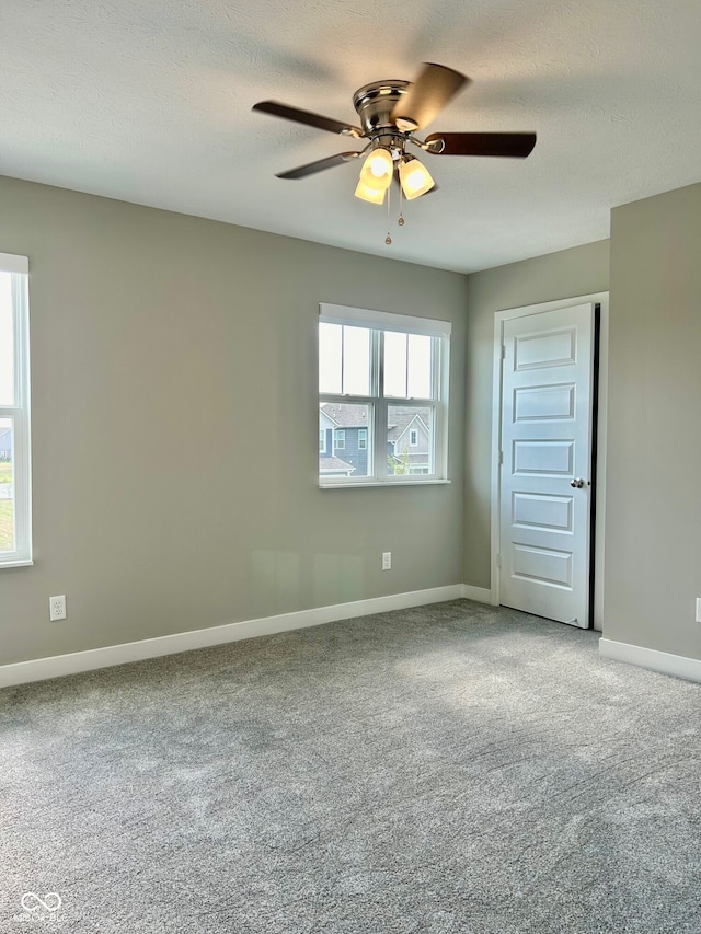 carpeted empty room with ceiling fan and a textured ceiling