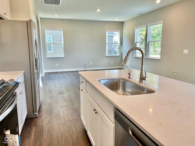 kitchen featuring white cabinets, light stone counters, stainless steel appliances, sink, and dark wood-type flooring