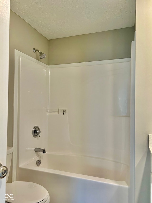 bathroom featuring a textured ceiling, toilet, and bathing tub / shower combination