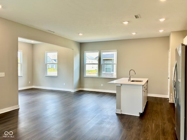 kitchen featuring stainless steel refrigerator, white cabinetry, sink, dark hardwood / wood-style floors, and a kitchen island with sink