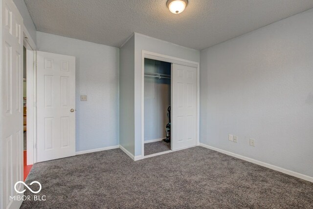 unfurnished bedroom featuring carpet, a textured ceiling, and a closet