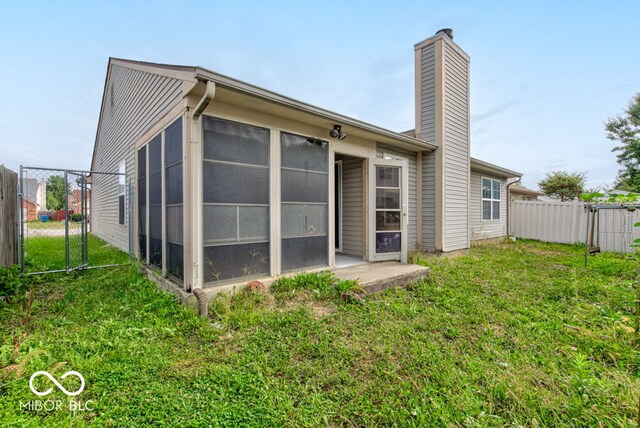 rear view of property featuring a sunroom and a yard