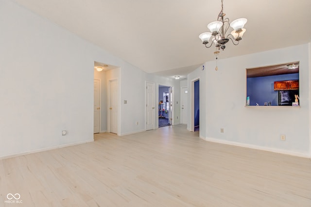 empty room with lofted ceiling, light wood-type flooring, and an inviting chandelier